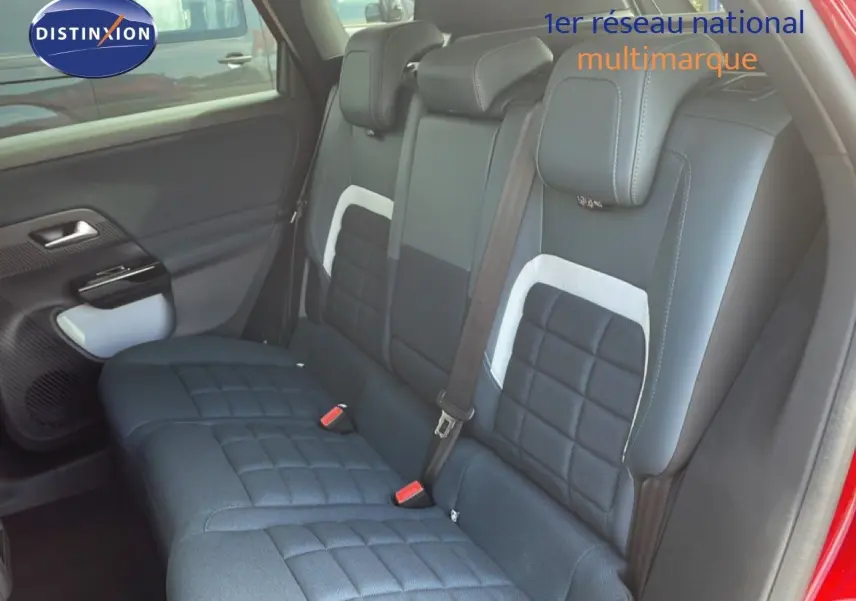 Vue intérieure côté arrière droit du Citroën C5 Aircross Hybrid rouge rubis, montrant les sièges arrière en tissu noir avec détails blancs.