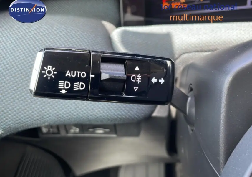 Gros plan sur la commande des feux et clignotants à gauche du volant dans un Citroën C5 Aircross Hybrid rouge rubis métal.