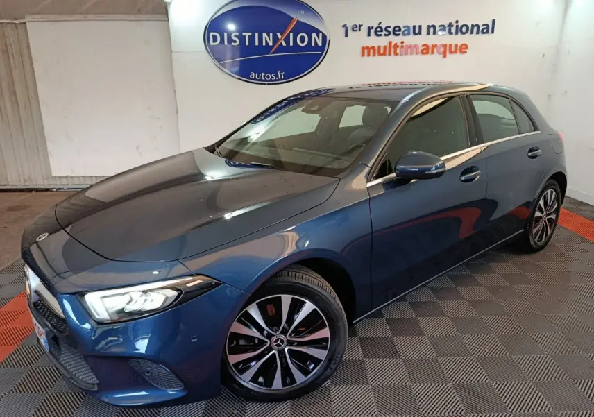 Mercedes Classe A 250 e Business Line bleu, vue 3/4 avant droit avec phares LED allumés et jantes distinctives.
