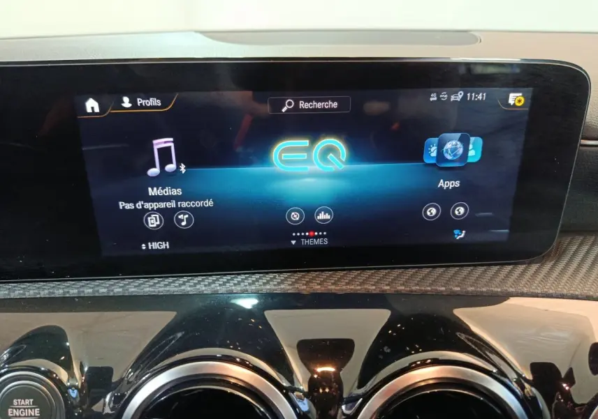 Gros plan sur l’écran tactile central et les aérateurs ronds noirs du tableau de bord de la Mercedes Classe A bleu.