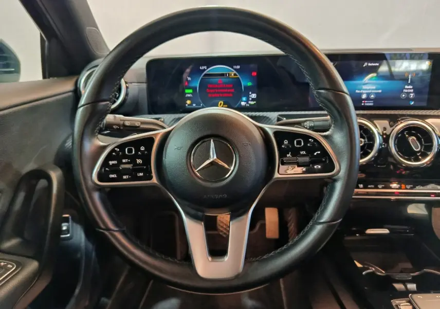 Vue intérieure centrée sur le volant cuir noir d'une Mercedes Classe A 250 e avec tableau de bord digital.