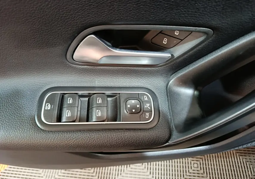 Détail de la porte côté gauche d’une Mercedes Classe A bleu, montrant les commandes des vitres et rétroviseurs.