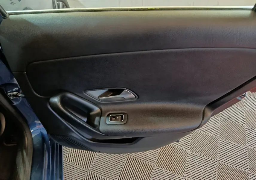 Vue intérieure côté gauche de la porte avant bleu foncé de la Mercedes Classe A 250 e Business Line avec poignée et bouton de vitre électrique.