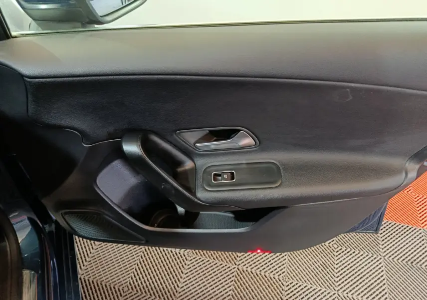Vue intérieure côté gauche de la porte avant d'une Mercedes Classe A 250 e Business Line bleu avec commandes de fenêtre.