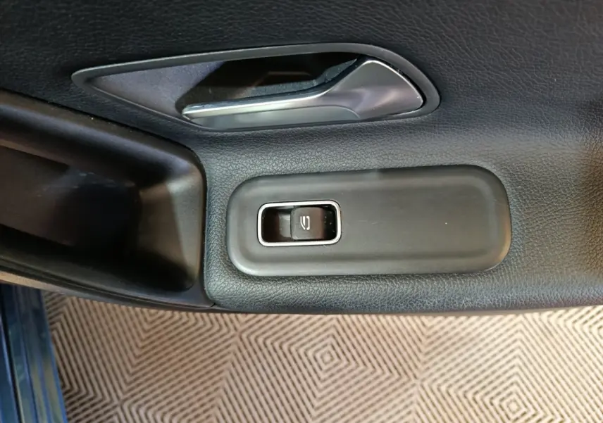 Gros plan sur la commande de lève-vitre côté conducteur d'une Mercedes Classe A 250 e Business Line bleu.