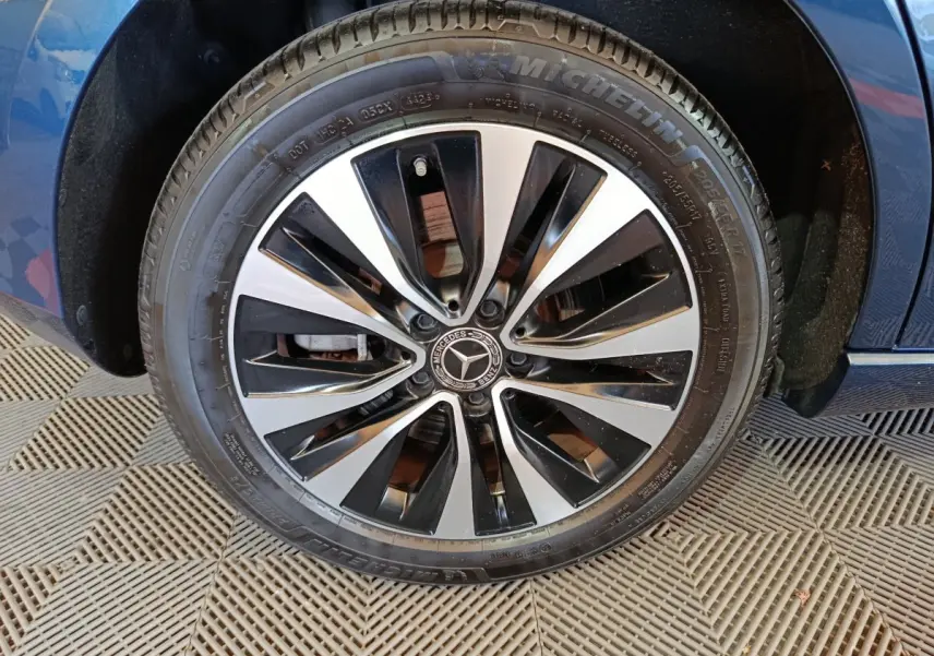 Gros plan sur la roue avant droite d’une Mercedes Classe A bleu, jante alliage noir et argentée design moderne.