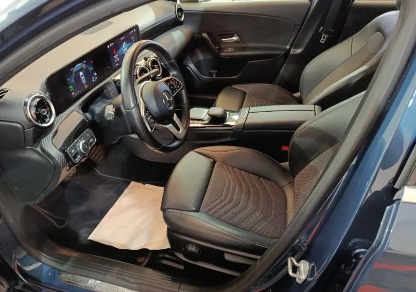 Vue intérieure côté conducteur de la Mercedes Classe A 250 e Business Line bleu, volant cuir et écran tactile visible.