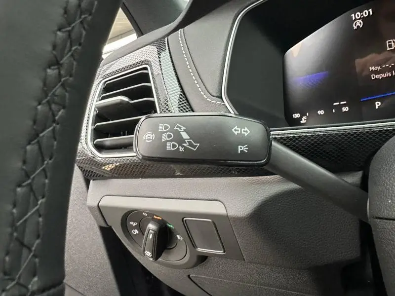 Gros plan sur la commande des clignotants et phares à gauche du volant, intérieur noir avec détails carbone du Volkswagen T-Cross 2026.