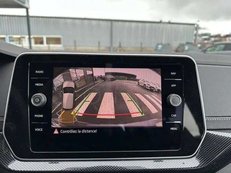 Écran tactile intérieur montrant la caméra de recul avec guidage, dans un Volkswagen T-Cross jaune 2026.