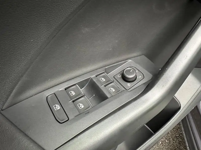 Gros plan sur les commandes de lève-vitres et rétroviseurs côté conducteur du Volkswagen T-Cross jaune 2026 R-Line.