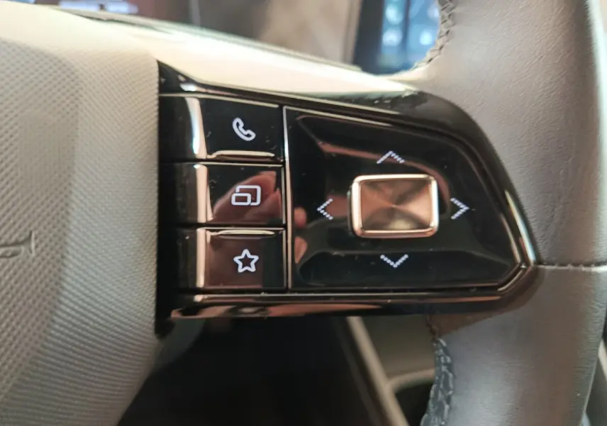 Gros plan sur les commandes noires multifonctions au volant cuir du MG3 gris foncé 2024, côté droit.