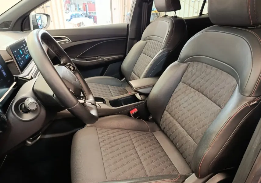 Vue intérieure côté conducteur du MG3 1.5L Hybrid+ Luxury 2024, sièges cuir noir avec surpiqûres rouges et tableau de bord digital.