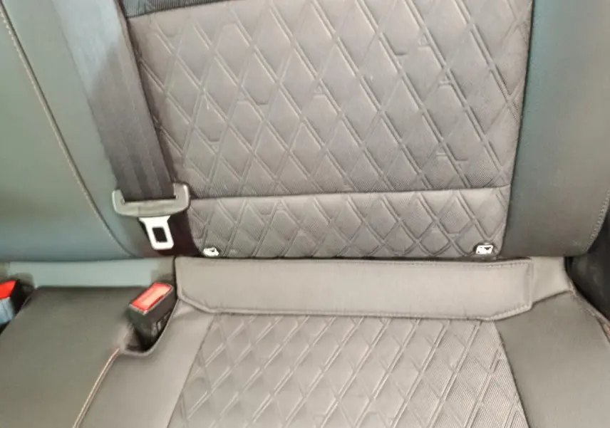 Gros plan sur la banquette arrière gris foncé matelassée du MG3 1.5L Hybrid+ Luxury 2024 avec ceinture de sécurité visible.