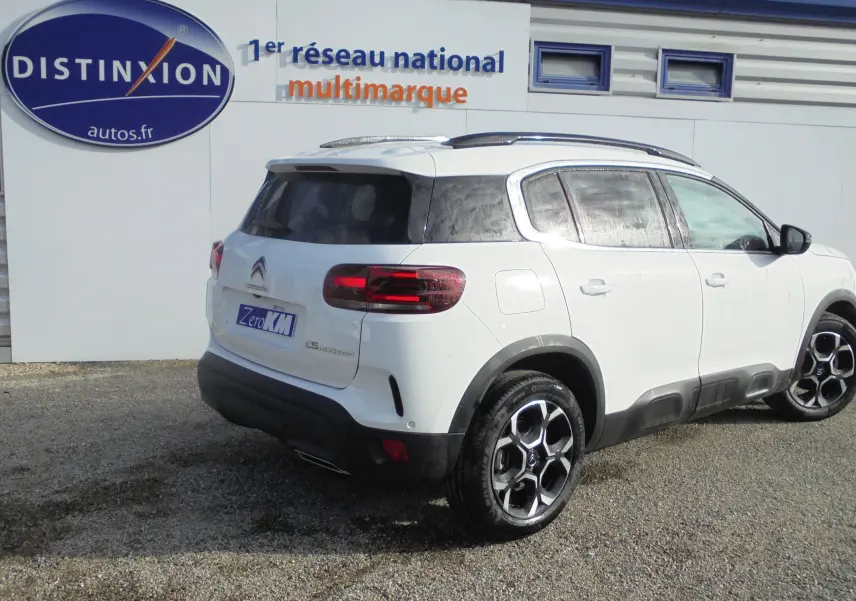 Vue 3/4 arrière droite d'un Citroën C5 Aircross blanc banquise avec jantes noires et toit panoramique.