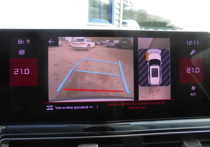 Écran multimédia montrant la caméra de recul et l'affichage 360° du Citroën C5 Aircross blanc banquise en stationnement.