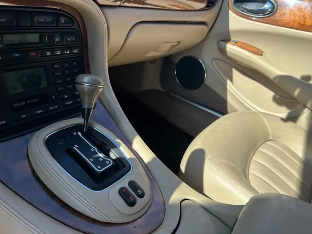 Intérieur beige clair de la Jaguar Sovereign 3.2 V8 2002, vue rapprochée de la console centrale avec levier de boîte auto.