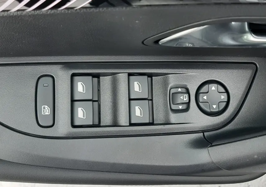 Gros plan sur les commandes des vitres et rétroviseurs côté conducteur d'un Peugeot 2008 gris Artense 2025.
