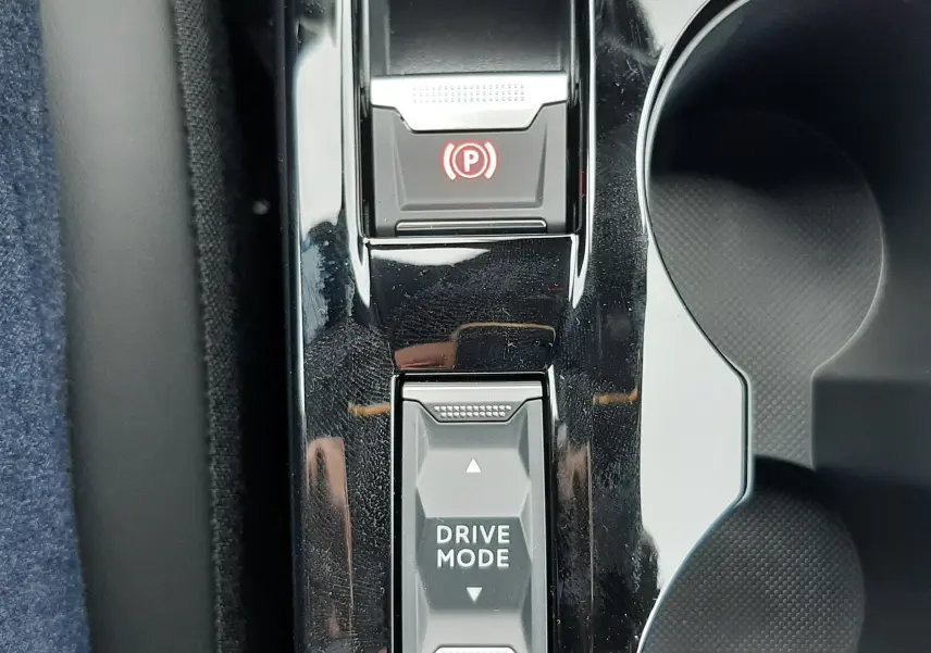 Vue rapprochée du levier de sélection Drive Mode et frein à main électronique sur la console centrale noire d'un Peugeot 2008 gris Artense.