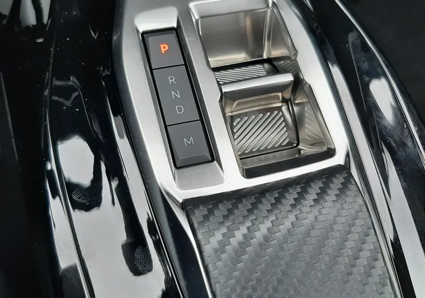 Gros plan sur la commande de boîte automatique avec bouton P rouge et surface effet carbone dans un Peugeot 2008 gris Artense.