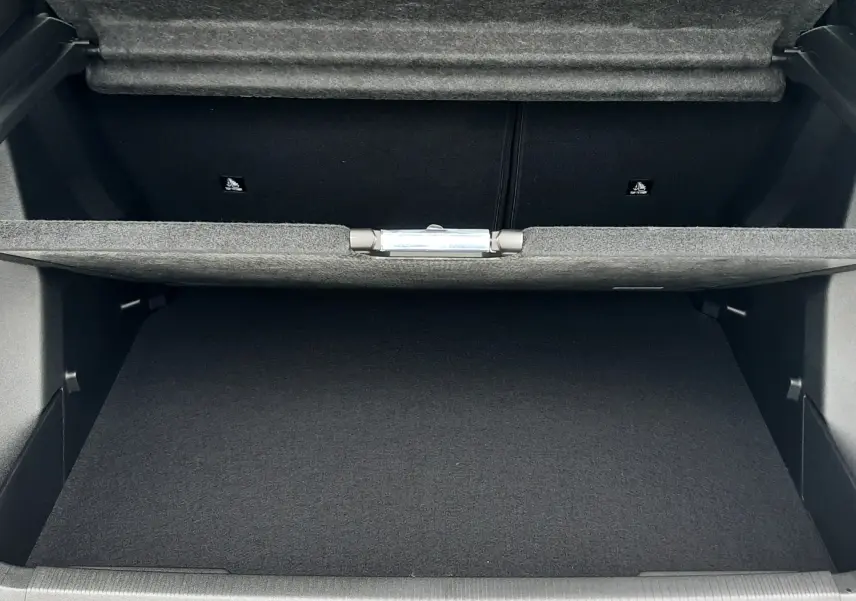 Coffre ouvert du Peugeot 2008 gris Artense, vue de l'arrière montrant l'espace de rangement et la doublure intérieure noire.