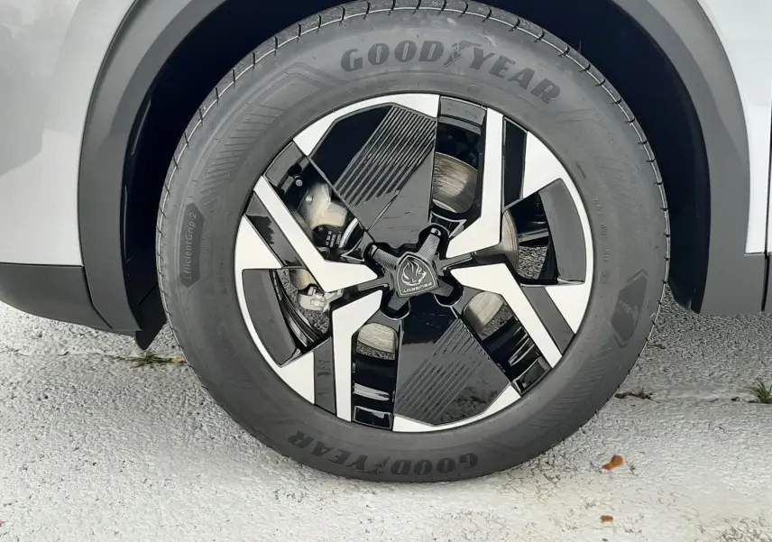 Gros plan sur la roue avant droite d'une Peugeot 2008 gris Artense avec jante noire et argentée au design moderne.