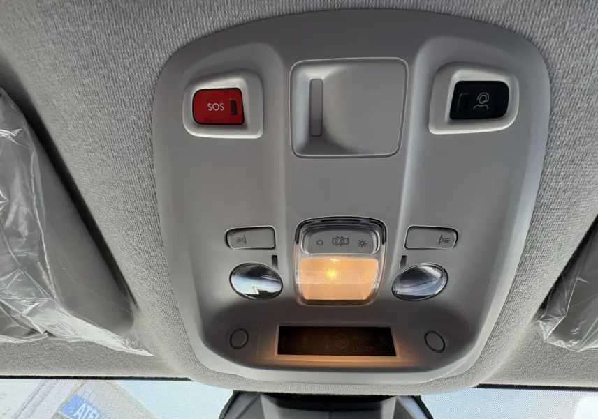 Vue en contre-plongée du plafonnier gris clair avec boutons SOS et éclairage intérieur allumé dans un Opel Vivaro blanc 2024.