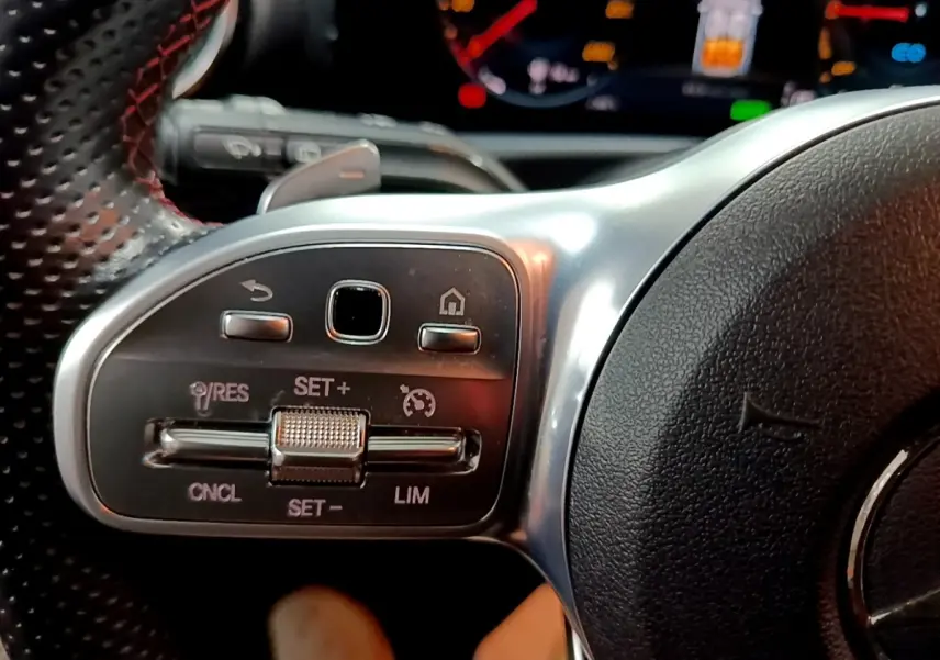 Gros plan sur le côté gauche du volant cuir et alu de la Mercedes Classe A 250 e AMG Line avec commandes multifonctions.