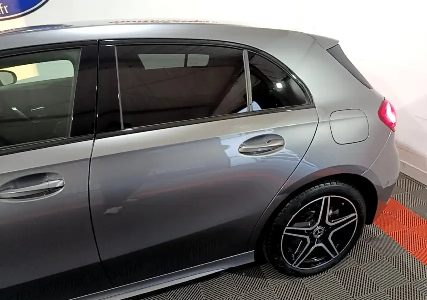 Vue latérale droite d'une Mercedes Classe A 250 e AMG Line gris foncé, avec jantes alliage noires et feux arrière allumés.