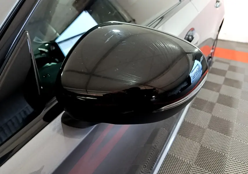 Gros plan sur le rétroviseur côté gauche noir brillant d’une Mercedes Classe A A 250 e AMG Line gris foncé.