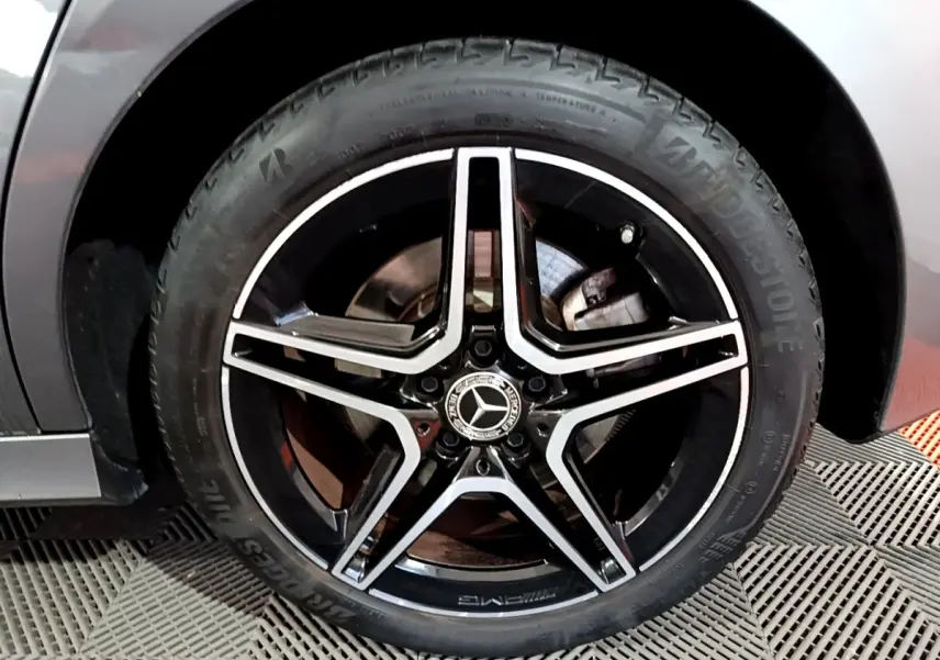 Gros plan sur la jante AMG noire et argent d'une Mercedes Classe A 250 e gris foncé, vue côté gauche.