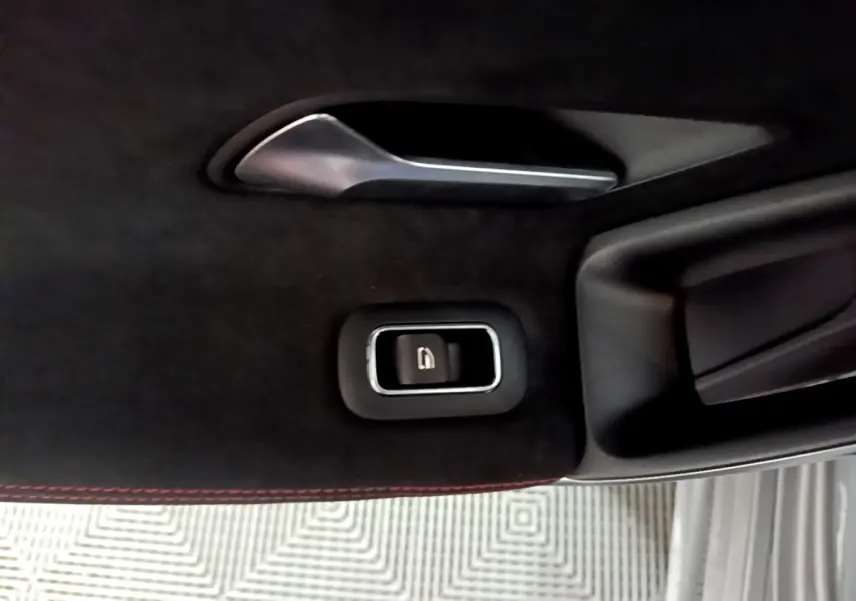 Gros plan sur la poignée intérieure et le bouton de verrouillage de porte, garniture noire avec surpiqûres rouges, Mercedes Classe A.