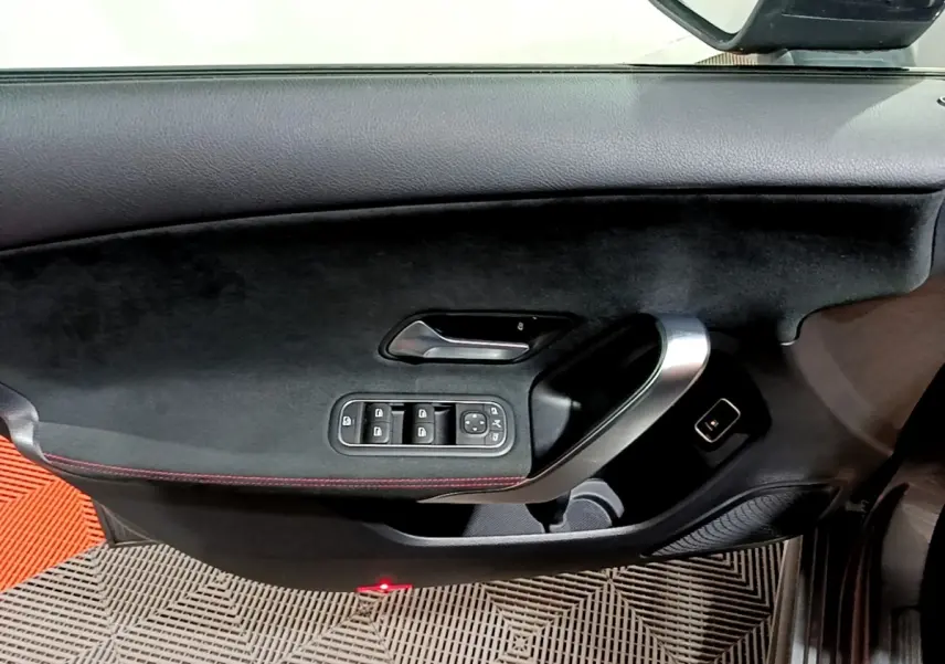 Vue intérieure côté gauche de la porte d’une Mercedes Classe A 250 e AMG Line 2021 avec garniture noire et poignée alu.