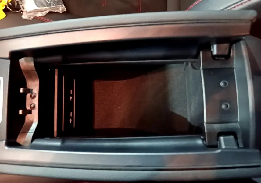 Vue plongeante sur le rangement central noir de la Mercedes Classe A 250 e AMG Line 2021 avec coutures rouges visibles.