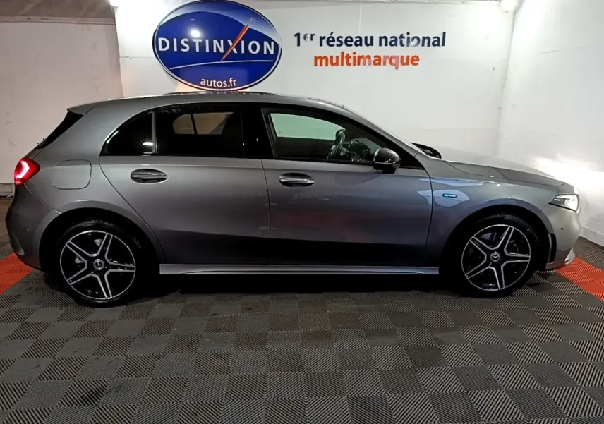 Vue latérale droite d'une Mercedes Classe A 250 e AMG Line gris foncé avec jantes AMG et feux arrière allumés.