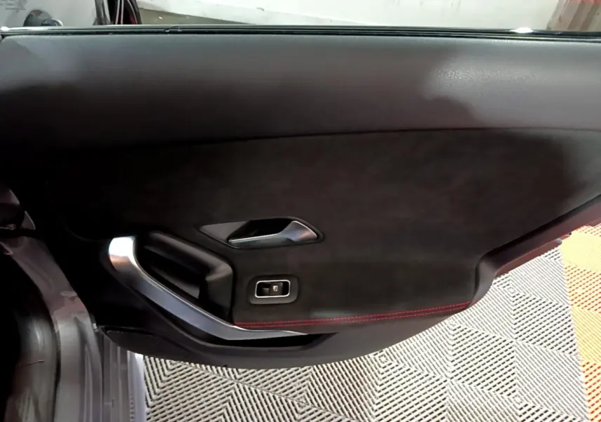 Gros plan sur la porte intérieure côté gauche de la Mercedes Classe A A 250 e AMG Line, avec finition noire et surpiqûres rouges.