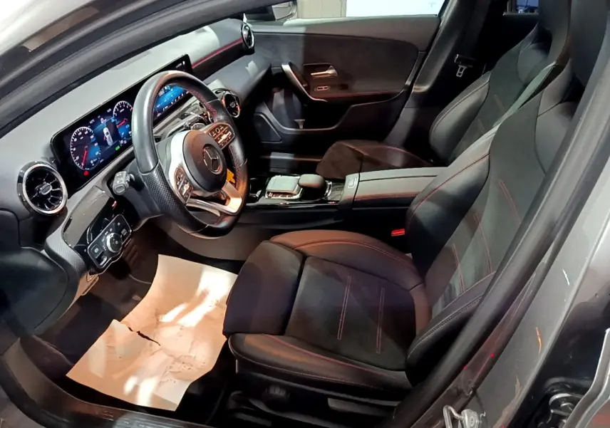 Vue intérieure côté conducteur de la Mercedes Classe A 250 e AMG Line 2021 avec sièges noirs et volant cuir alu multifonctions.