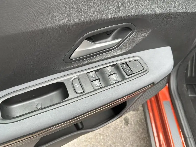 Gros plan sur la commande des vitres électriques et rétroviseurs sur la porte avant gauche du Dacia Jogger brun Terracota.