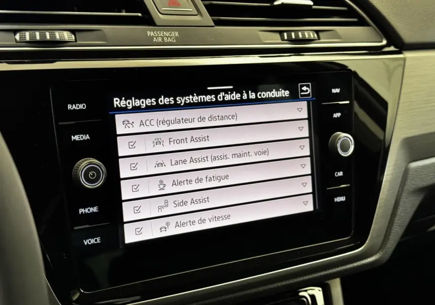Écran tactile central du Volkswagen Touran 2024 affichant les réglages des aides à la conduite dans l'habitacle.