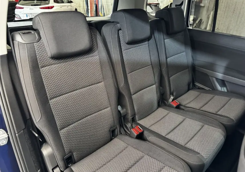 Vue rapprochée des trois sièges individuels arrière en tissu gris foncé du Volkswagen Touran 2024 bleu.