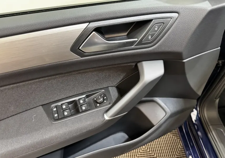 Vue intérieure sur la porte avant gauche bleu foncé d'un Volkswagen Touran 2024 avec commandes de vitres et verrouillage.