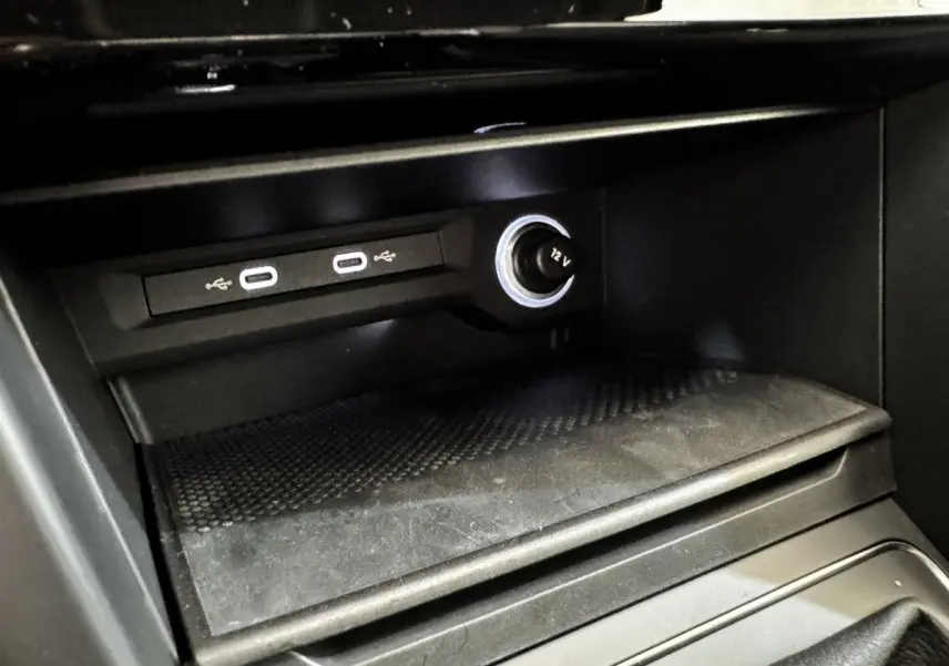 Gros plan intérieur sur la console centrale noire du Volkswagen Touran 2024 avec ports USB-C et prise 12V éclairée.