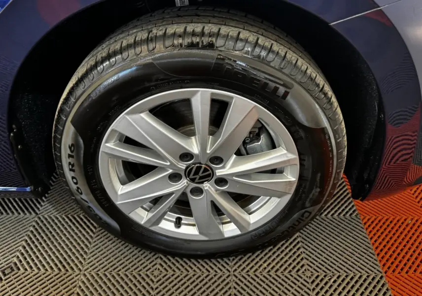 Gros plan sur la roue avant droite du Volkswagen Touran bleu 2024, avec jante alliage argentée et pneu Pirelli.