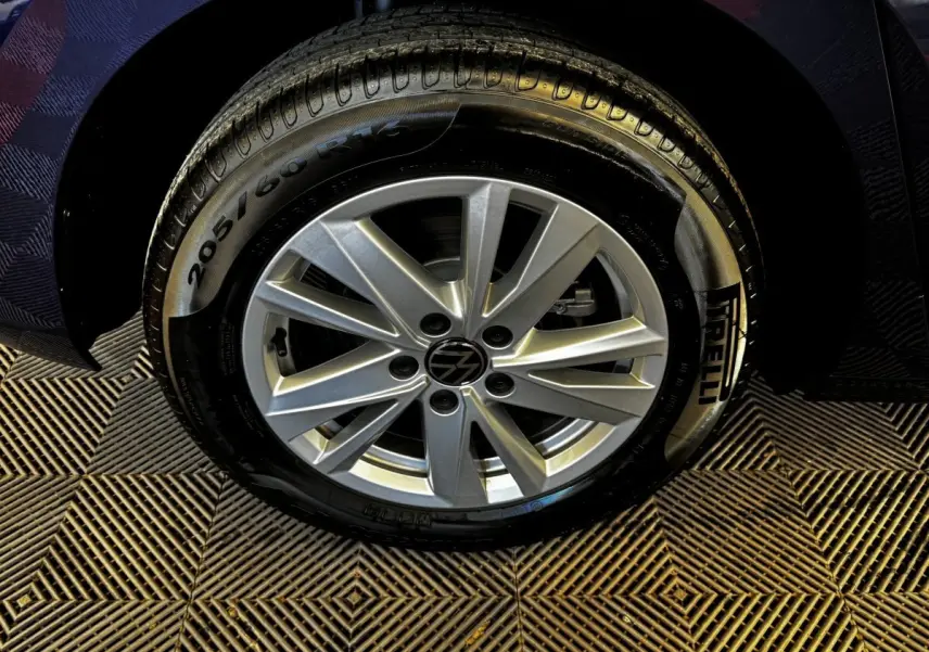 Gros plan sur la roue avant droite du Volkswagen Touran bleu 2024 avec jante alliage et pneu Pirelli.