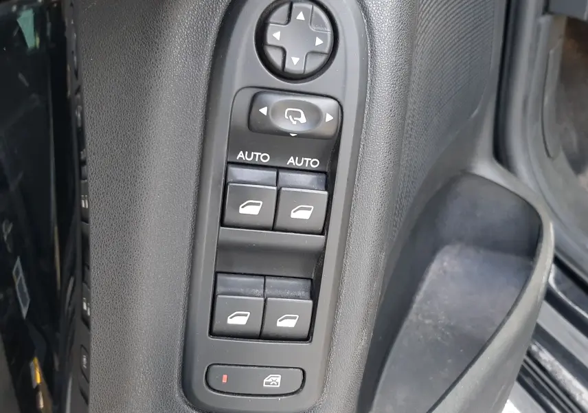 Panneau de commandes des vitres électriques et rétroviseurs sur la porte côté gauche d'une Citroën C3 noire de 2016.