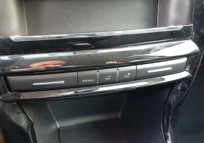 Gros plan sur la console centrale noire brillante de la Citroën C3 BlueHDi 75 Exclusive avec boutons de menu et réglage du volume.