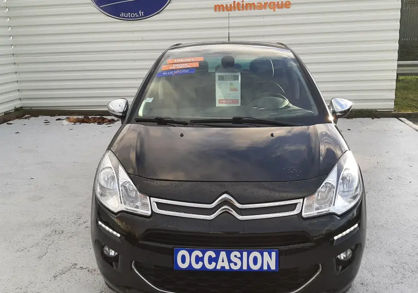 Vue frontale d'une Citroën C3 noire de 2016 avec plaques "OCCASION" et stickers diesel et Bluetooth sur le pare-brise.