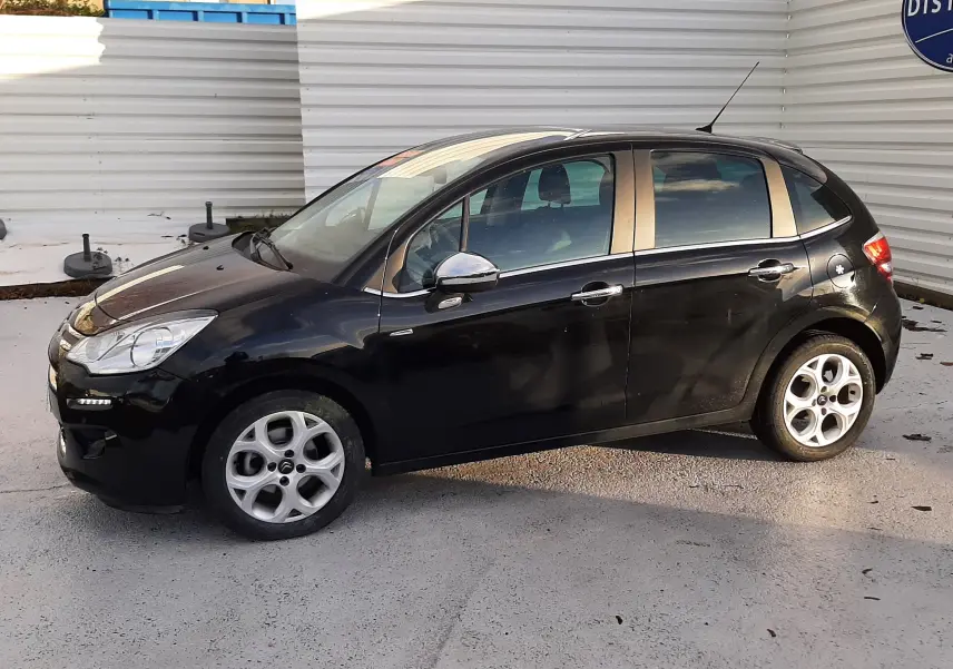 Citroën C3 noire vue de profil côté gauche, avec jantes alliage et rétroviseurs chromés sur fond urbain.