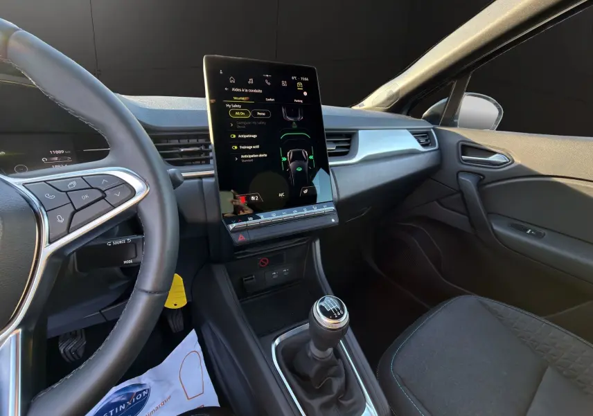 Vue intérieure côté conducteur du Renault Captur 2024, montrant la console centrale avec écran tactile vertical et levier de vitesse manuel.