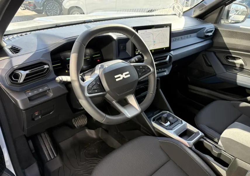 Vue intérieure côté conducteur du Dacia Duster 2024 hybride, avec volant multifonction et écran tactile central.