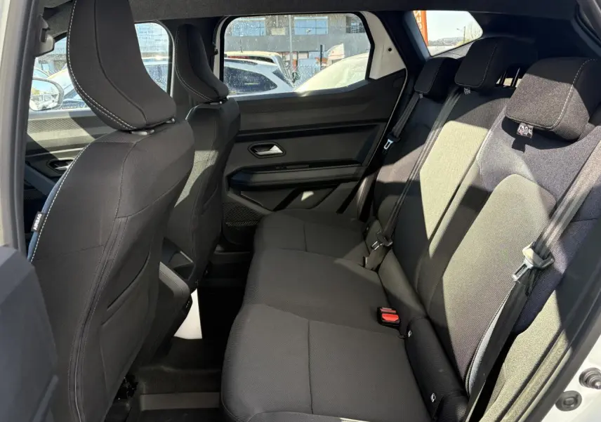 Vue intérieure côté droit de la banquette arrière noire du Dacia Duster 2024 avec appuie-têtes et ceintures de sécurité visibles.